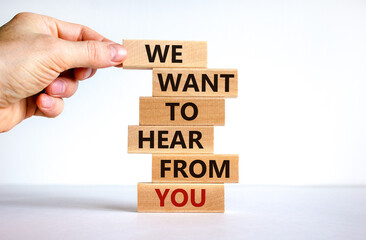 Support symbol. Wooden blocks with words 'we want to hear from you'. Male hand. Beautiful white background. Copy space. Business and support concept.