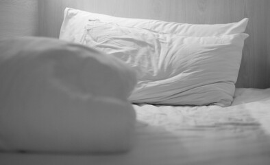 Soft and calm atmosphere image of all white bed room. Pillows, blanket and towels on empty bed, close up. Image blurred.