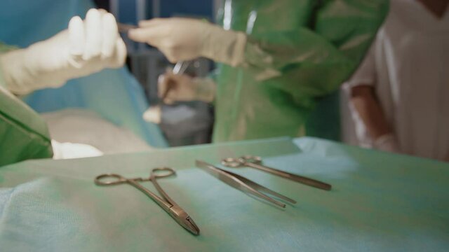Close up of unrecognizable hands of medical assistant handing surgical scissors to professional surgeon during operation