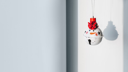 Snowman with red hat, decoration for Christmas tree. New Year decorative bell on grey background...