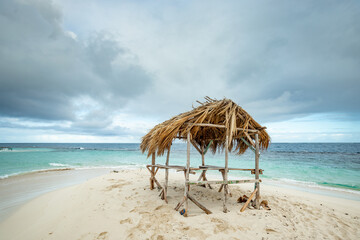 Wooden gazebo with palm tree leaves roof on the white sand of the paradise beach in Atlantic Ocean, Cayo Arena, Punta Rucia, Dominican Republic