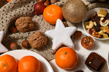 sweet food background for christmas or holiday decoration - chocolate candies, tangerines, nuts and dried fruits on white wood