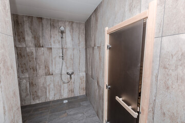 Tiled shower room and glass door to spacious wooden sauna