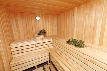Fototapeta na wymiar Huge wooden spacious beautiful sauna in which birch brooms lying on a bench