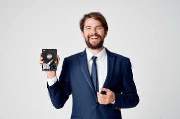 a man in a suit holds an unassembled hard drive in his hand and a gray background