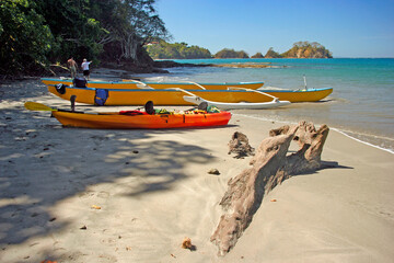 Fototapeta premium Driftwood and outrigger canoes on the beach at Puntarenas on Nicoya Peninsula, Costa Rica