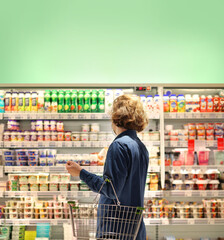 Supermarket shopping, face mask and gloves,Young man shopping in supermarket, reading product information.