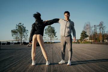 friends trainers muscle stretching Man and woman African American in sports comfortable clothing for aerobics fitness training on the waterfront in the city. couple playing sports outside