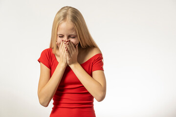 Teenage girl with blond hair and in a red dress sneezes