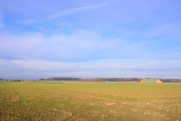 Wide landscape in Bavaria in autumn with harvested fields, a small village and a blue sky with clouds