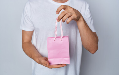 Fototapeta na wymiar model man with gift bag in hand on light background holidays