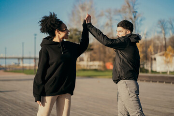 sports couple in love a young man and a woman of different ethnicities, doing sports fitness cardio training aerobics in the Park in the city center on the embankment. Sports wear comfortable