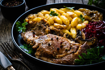 Roasted pork steaks, noodles and pickled beetroot and onion on wooden table
