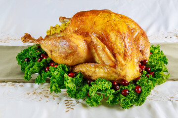 Thanksgiving dinner table served with turkey, decorated with kale and cranberry.