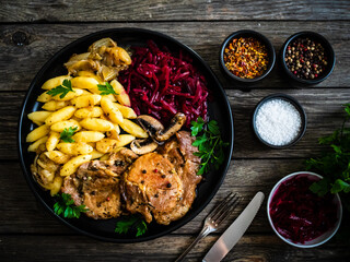 Roasted pork steaks, noodles and pickled beetroot and onion on wooden table
