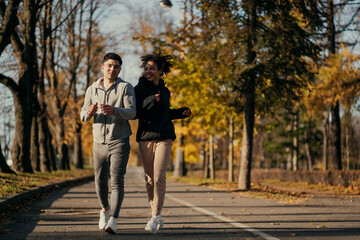 Obraz premium cardio fitness aerobics exercise in the Central Park of the city. do active stretching fitness exercises on the street. a strong pair of European male and African American female.
