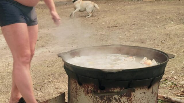 Fat man with big belly cooks fish on fire in the forest. Summer activities.