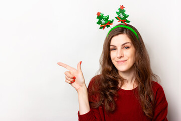 Girl with long hair in a red sweater and a festive headband with shiny Christmas trees on a spring....
