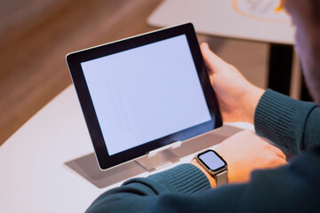 Businessman with digital tablet with white screen on the table and smart watch on his hand. A male freelancer works in a cafe.