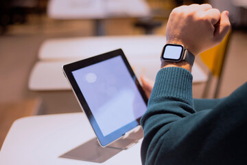 Businessman with digital tablet with white screen on the table and smart watch on his hand. A male freelancer works in a cafe.