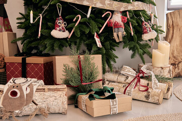 Beautiful holdiay DIY handmade home decoration. Cosy room decorated with candles and Christmas tree with presents under it. Hot drink on the table. New Year's interior in a photo studio
