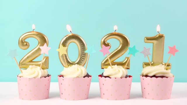 2021 Happy New Year's Eve pastel pink and blue theme cupcakes with large gold candles. Cinemagraph continuous loop.