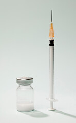 syringe with orange cannula, vaccine in glass vial, with blue background