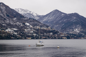 boat docked in front of beautiful snowy mountain lake Como