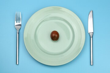 cherry tomato on a plate with knife and fork on blue background 