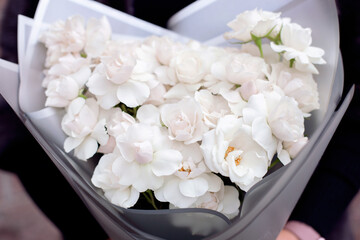 Female hands with beautiful winter flowers, white roses and peonies