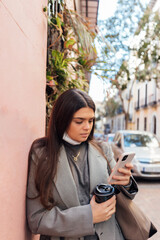 Young woman using smart phone while drinking