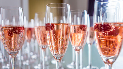 Refreshing, effervescent raspberry champagne in multiple clear flutes