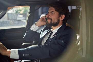 man in a suit driving a car success official talking on the phone