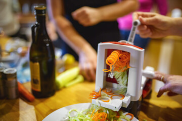 Carrots and cucumbers spiralized into noodles using a spiralizer at a kitchen raw vegan party.