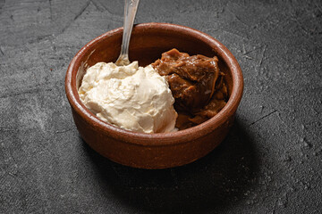 primer plano de bouls con rema chantilly batida y dulce de leche respostero sobre base gris