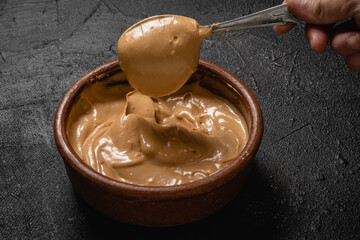 postre mezcla de crema con dulce de leche con cuchara sobre base gris para hacer chocotorta o...