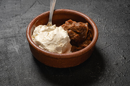 primer plano de bouls con rema chantilly batida y dulce de leche respostero sobre base gris