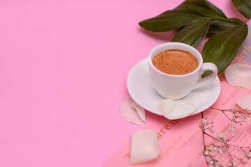 Cup of coffee with flower petals and green leaves on a pink background. Copy spase. Side view. High quality photo