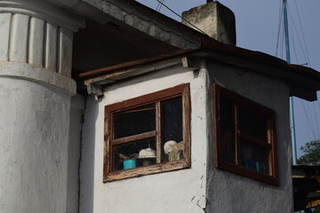 Fototapeta na wymiar small stone house with peeling plaster and wooden window