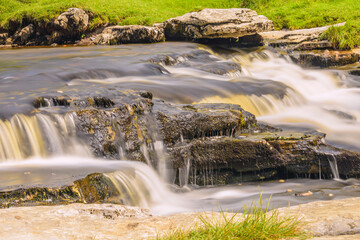 Waterfalls cascade surrounded by greenery and rocks