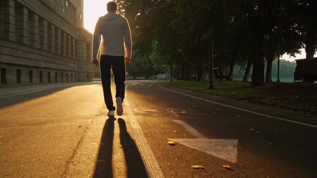 rear male with dog walk at dawn empty morning city walks at sun rays slow motion