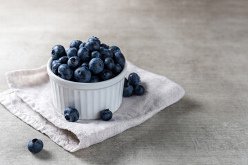 Lot of fresh delicious blueberries on a white pot over a wooden table