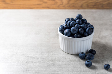 Lot of fresh delicious blueberries on a white pot over a wooden table