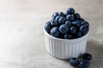 Lot of fresh delicious blueberries on a white pot over a wooden table