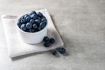 Lot of fresh delicious blueberries on a white pot over a wooden table