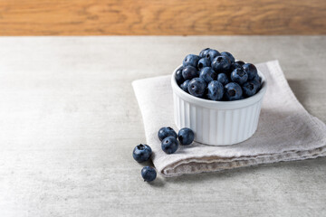 Lot of fresh delicious blueberries on a white pot over a wooden table
