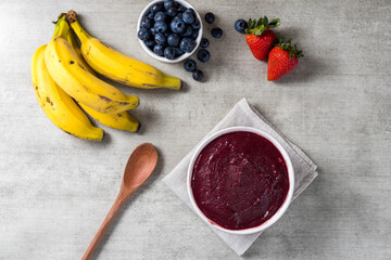 Brazilian frozen açai berry ice cream bowl. with fruits on wooden background. Summer menu top view. close up