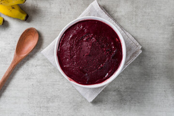 Brazilian frozen açai berry ice cream bowl. with fruits on wooden background. Summer menu top view. close up