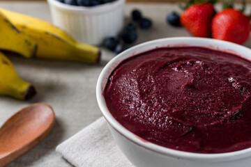 Brazilian frozen açai berry ice cream bowl. with fruits on wooden background. Summer menu front view
