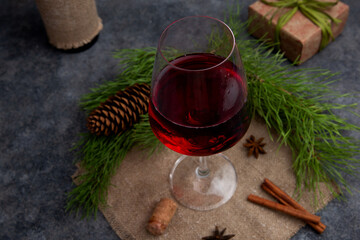 Red wine in a glass on a gray background with a bottle wrapped in jute or linen cloth on the background of a Christmas tree. The concept of the holiday, cozy Christmas, New year. Rustic style